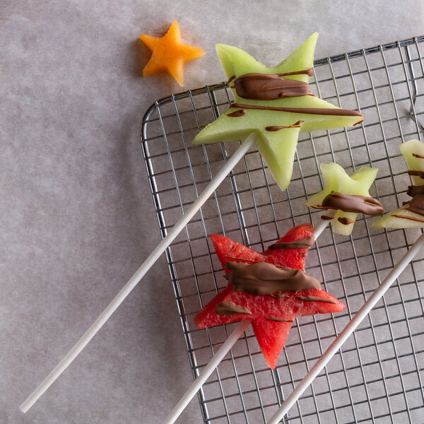 A star shaped fruit on a Paper Chocolate Rose Stick on a metal grid.