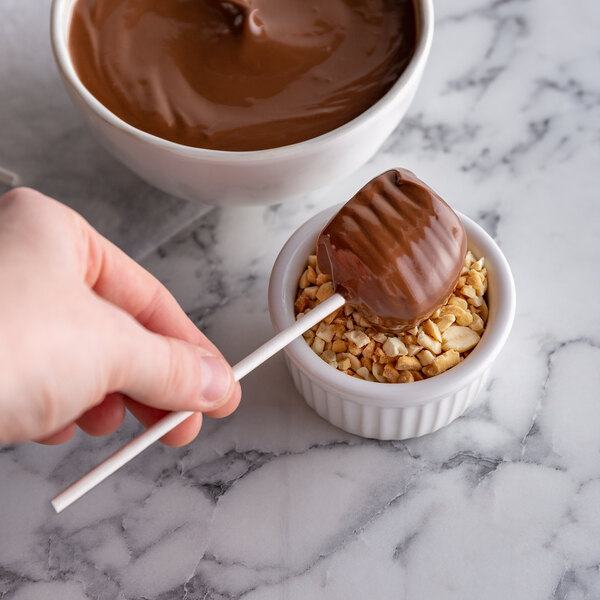 A Paper Lollipop stick with chocolate on it in a bowl of chocolate.