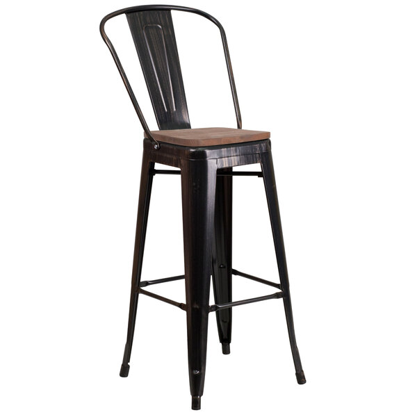 A Flash Furniture black metal bar stool with wood seat and vertical slat back on a table in a bar.