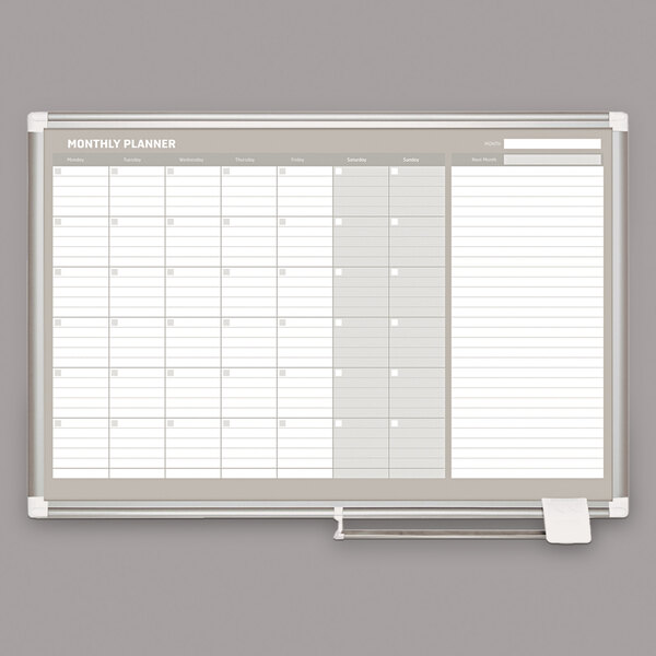 A white rectangular MasterVision dry erase board with a monthly calendar.