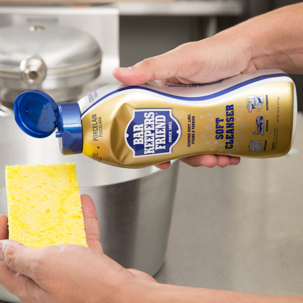 A person pouring Bar Keepers Friend All Purpose Soft Cleanser into a yellow sponge.