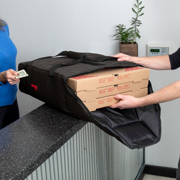 A man and woman using a Cambro pizza delivery bag to carry pizza boxes.