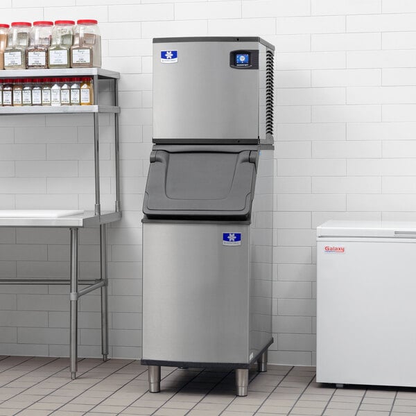A Manitowoc air cooled ice machine and ice bin in a kitchen.