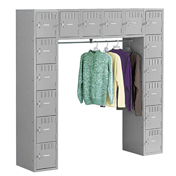 A close-up of a Tennsco medium gray steel locker with a coat bar and shirts hanging on it.