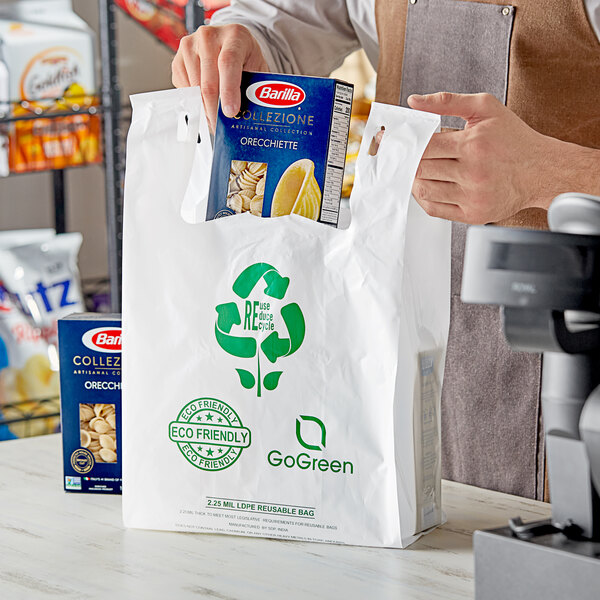 A man holding a white plastic t-shirt bag full of groceries in an organic food store.