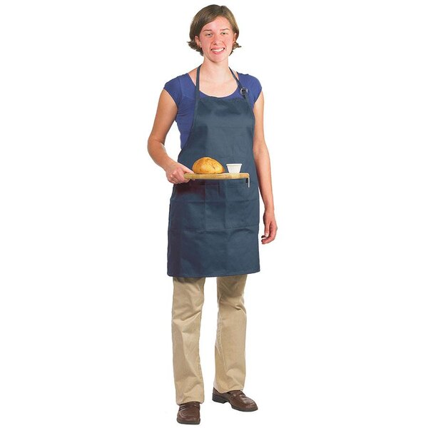 A woman wearing a navy blue Chef Revival bib apron holding a tray of bread.