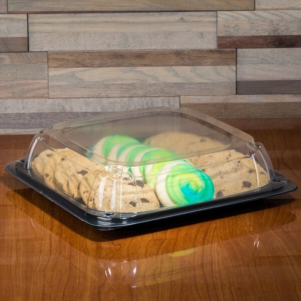 A clear plastic Sabert catering tray with cookies and green icing inside.