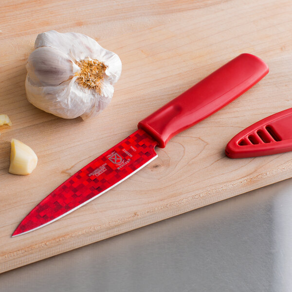 A red Mercer Culinary paring knife and garlic on a cutting board.