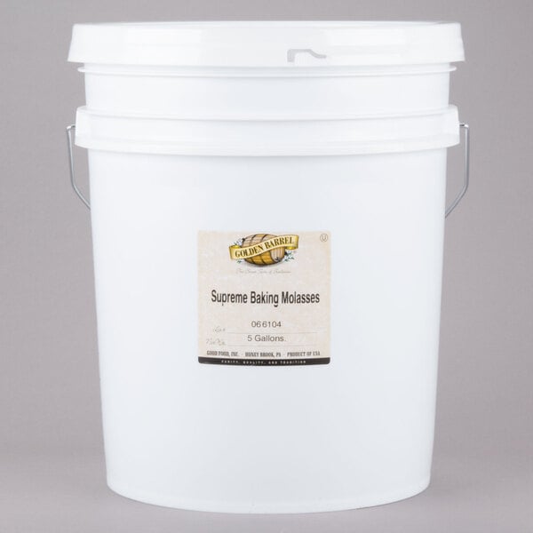 A white bucket with a white label containing Golden Barrel Supreme Baking Molasses.