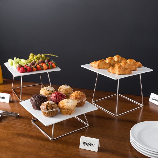 A table with a Acopa chrome wire riser set holding plates of food.