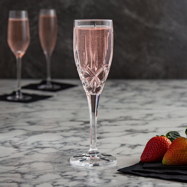 Two Nachtmann Noblesse champagne flutes filled with pink liquid next to strawberries.