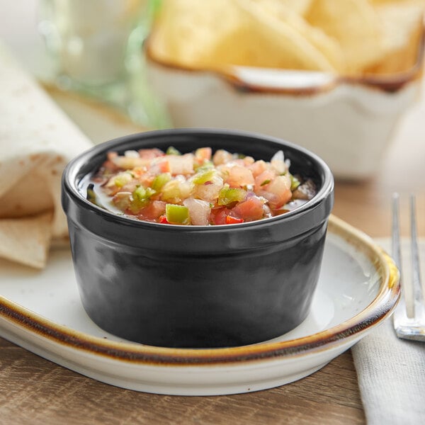 A white Acopa Keystone stoneware ramekin filled with salsa on a plate with tortilla chips.