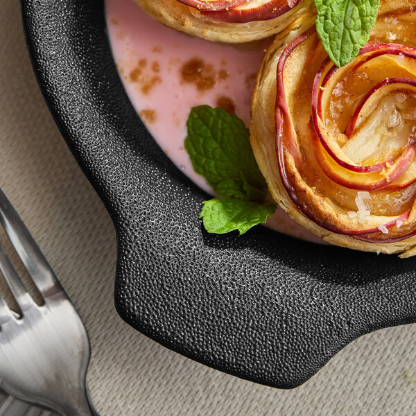 A black textured porcelain casserole dish containing a dessert garnished with mint leaves.