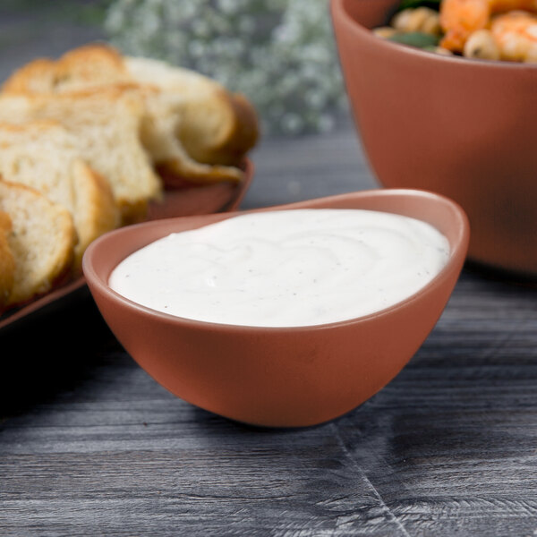 A Libbey Driftstone porcelain bowl filled with white sauce next to a bowl of bread.