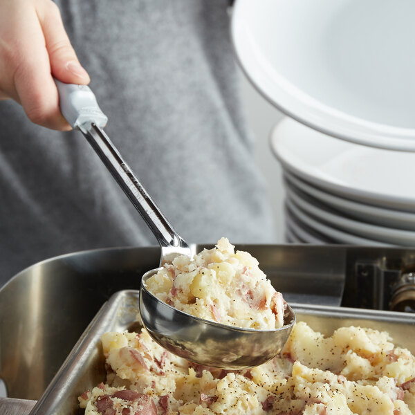 A hand using a Vollrath Spoodle to serve mashed potatoes.