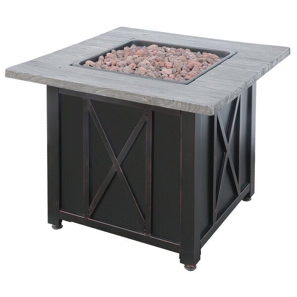 A square black metal fire pit table with a wood grain top with rocks in the center.