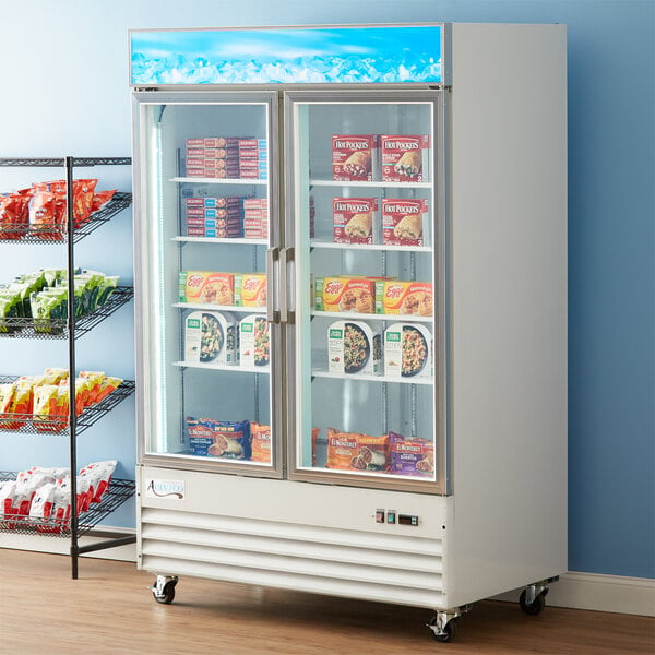 An Avantco white glass door merchandiser freezer with food and drinks inside.