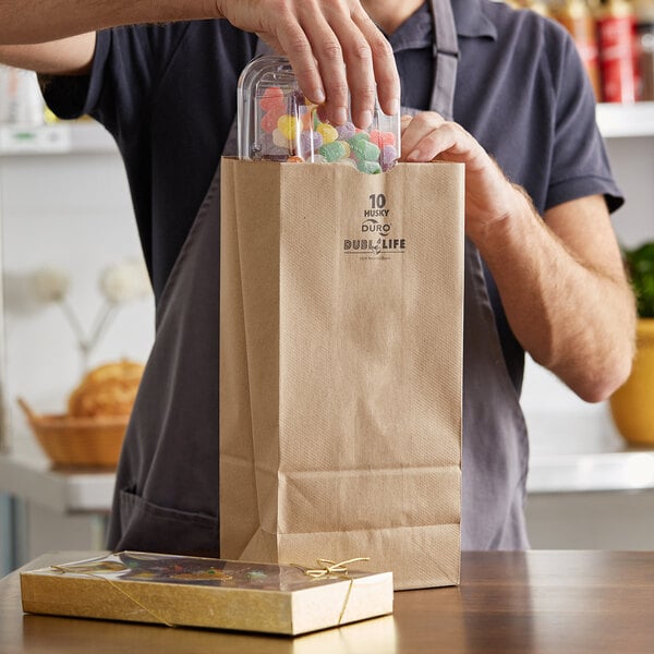 A man holding a brown Duro paper bag full of candy.