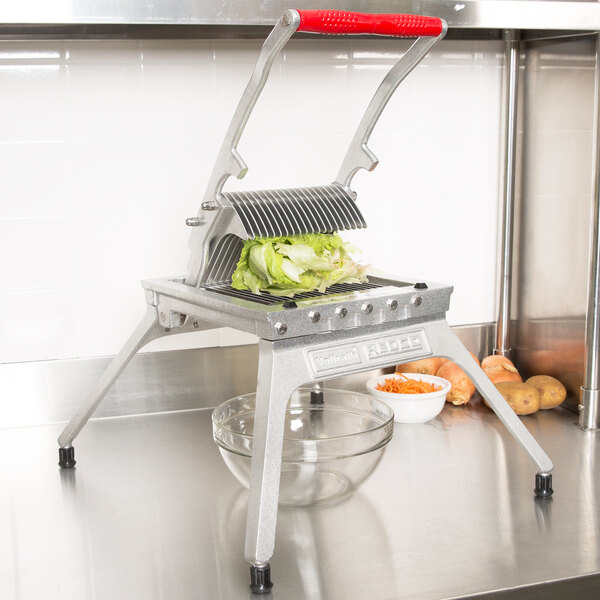 A Vollrath Redco Lettuce King vegetable cutter on a counter with a bowl of lettuce.