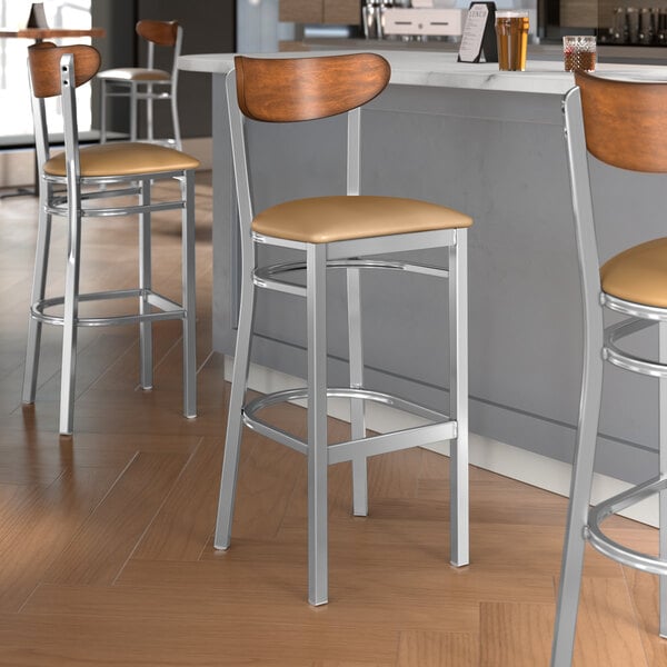 Lancaster Table & Seating Boomerang Series bar stools with light brown vinyl seats and antique walnut backs.