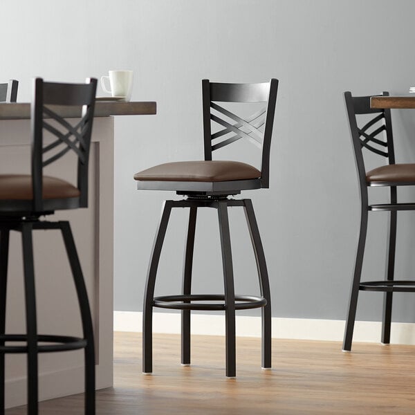 A Lancaster Table & Seating black swivel bar stool with a dark brown cushioned seat.