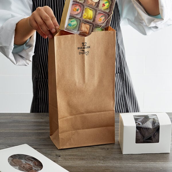 A person putting chocolate in a Duro Bulwark brown paper bag.