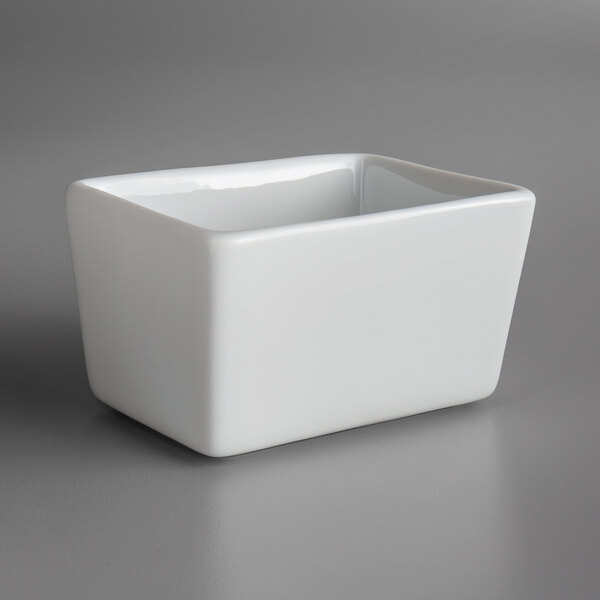 A Oneida Royale bright white porcelain square sugar caddy on a gray surface.