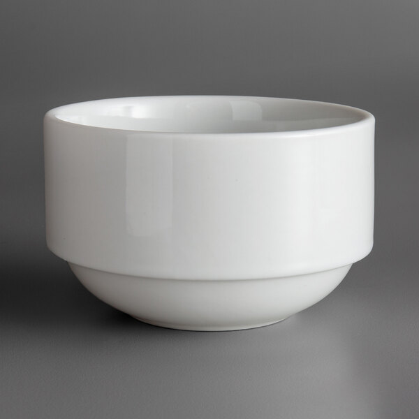 A stackable white porcelain soup bowl with a small rim on a gray surface.