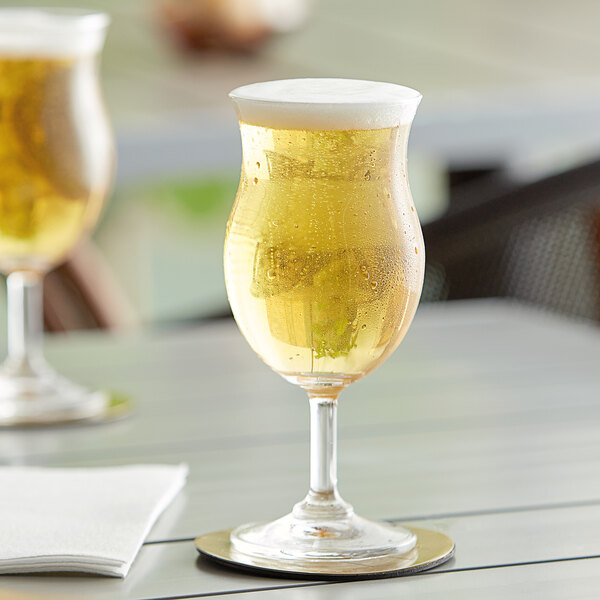 Two Acopa Select Belgian beer glasses filled with beer on a table.
