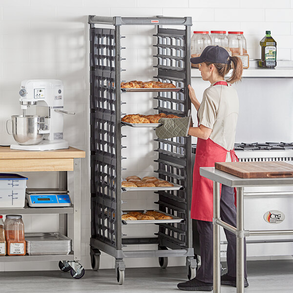 A woman in a red apron using a Cambro sheet pan rack to display doughnuts.