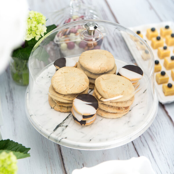 A plate of cookies covered by a Delfin clear acrylic dome cover.