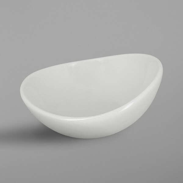 A RAK Porcelain ivory sauce dish with a curved edge on a gray surface.
