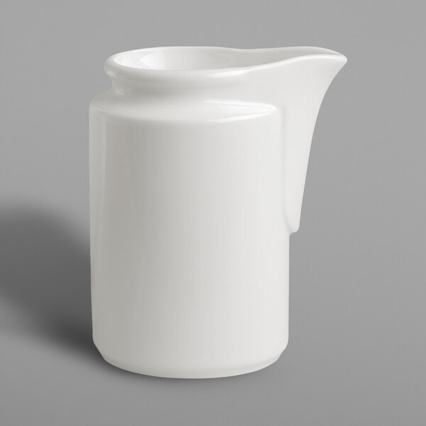 A white RAK Porcelain creamer with a lid on a gray surface.