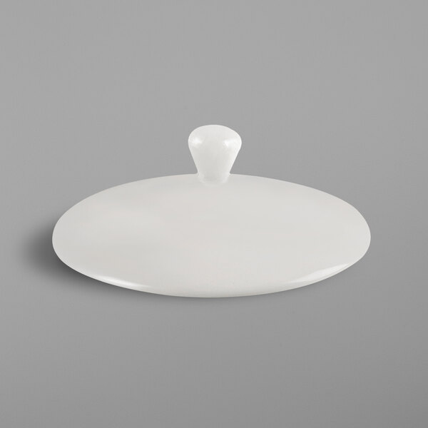 A close up of a white RAK Porcelain teapot lid with a knob.