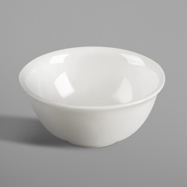 A RAK Porcelain ivory bowl with a small amount of food on a gray surface.