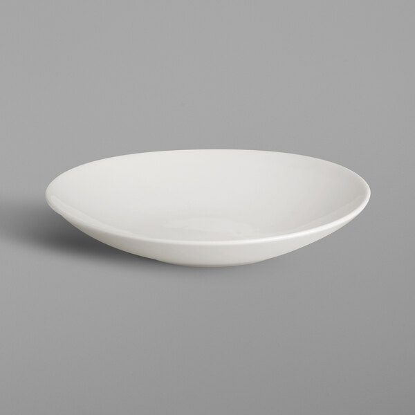 A RAK Porcelain ivory deep coupe plate with a silver spoon on it.