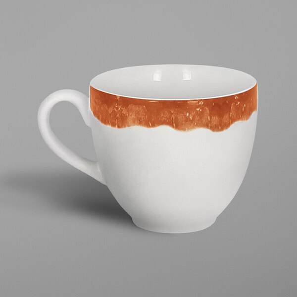 A white porcelain coffee cup with an orange cedar design on it.