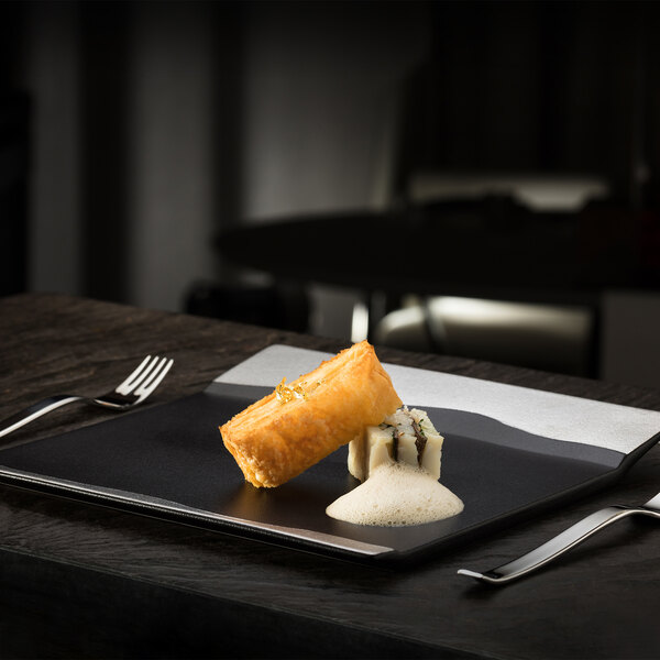 A RAK Porcelain black and silver rectangular platter with food on it on a table.