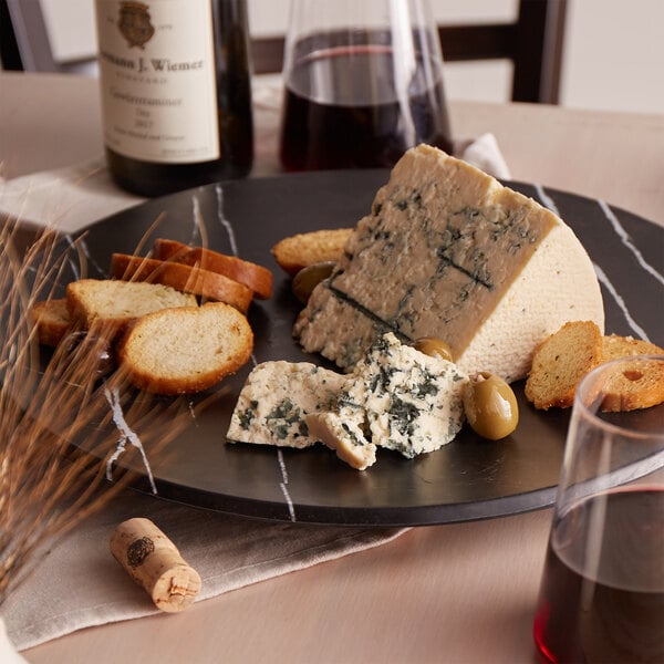 A plate with a piece of St. Clemens Blue Cheese and bread next to a glass of wine.