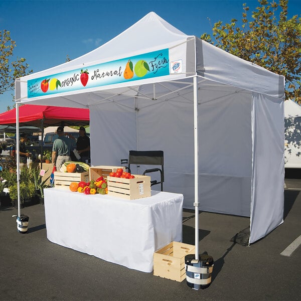A white E-Z Up canopy with white frame and vegetables on display.