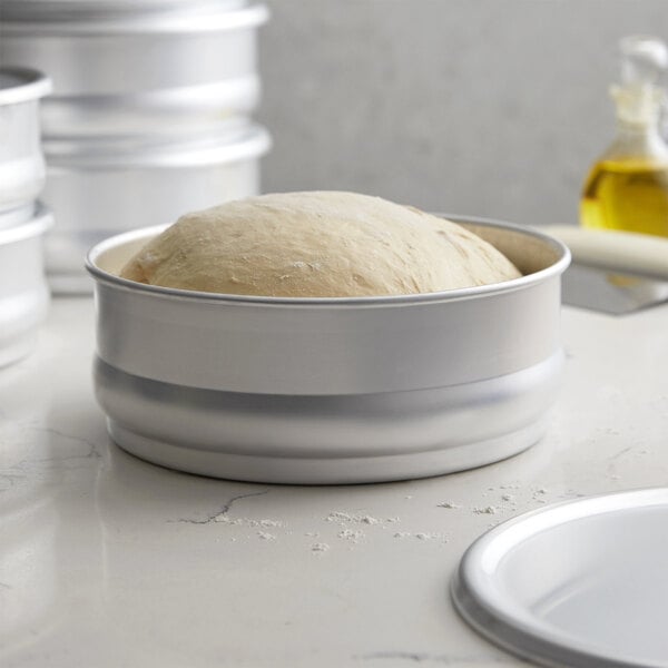 A round dough in a metal pan on a counter.