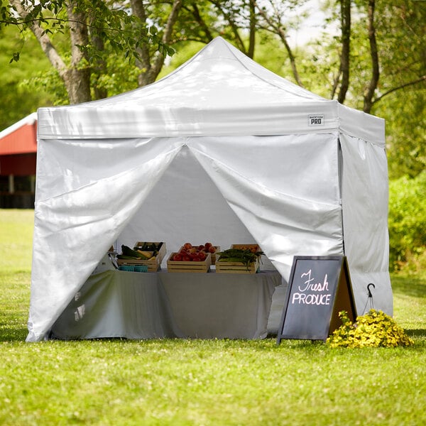 A white Backyard Pro canopy with walls set up on grass.