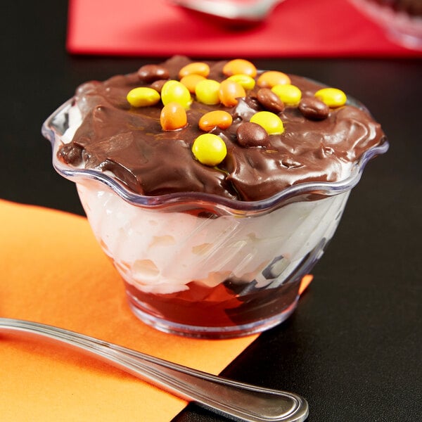 A clear tulip dessert dish filled with chocolate pudding, candy, and chocolate chips.