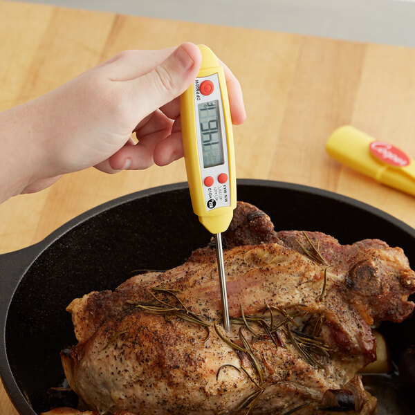 A person holding a white and yellow Cooper-Atkins digital pocket probe thermometer to a piece of meat.