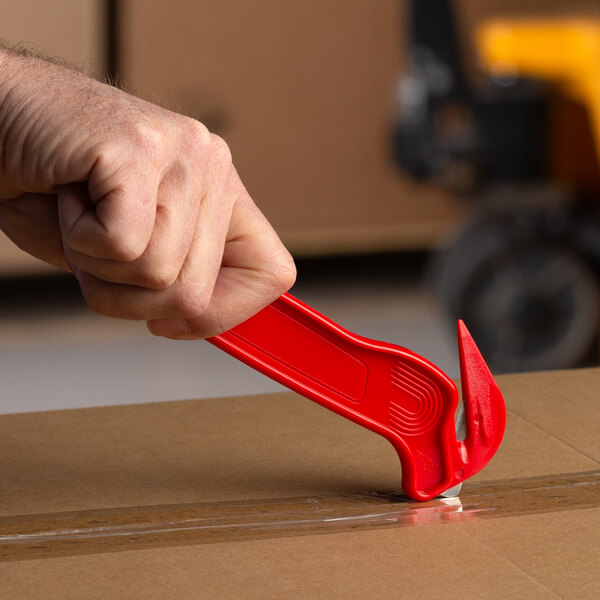 A person using a Pacific Handy Cutter red food safe box cutter to open a box.