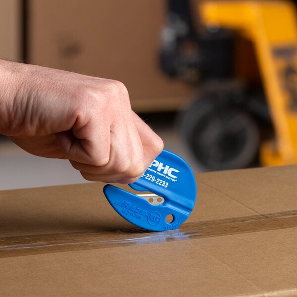 A person using a blue Pacific Handy Cutter to open a box.
