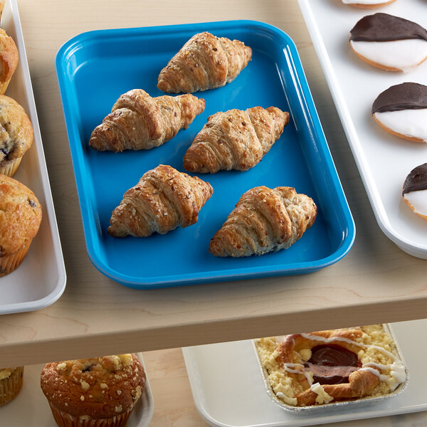 A blue Cambro market tray with pastries on a table.
