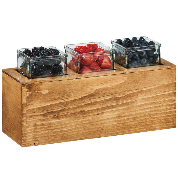 A Cal-Mil Madera rustic pine action station holding three glass jars of berries on a counter.