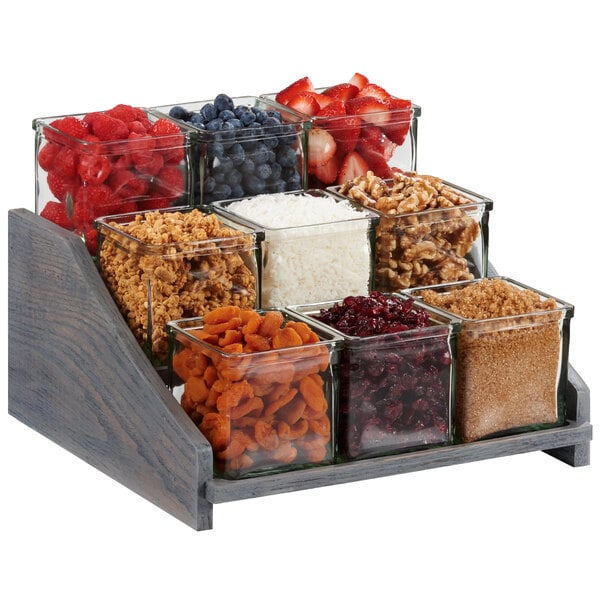 A Cal-Mil Ashwood Gray Oak display with glass jars filled with brown sugar, fruit, and nuts.