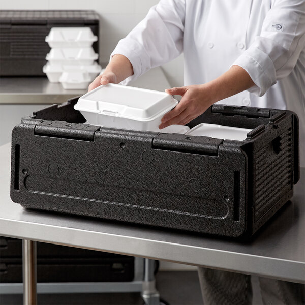 A person using a CaterGator Dash food pan carrier to hold a white container of food.